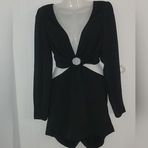 The image shows a black mini pants with long sleeves and a deep V-neckline.